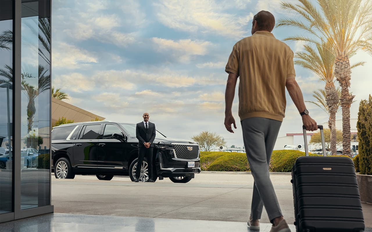 Traveler walking with luggage toward a waiting private car