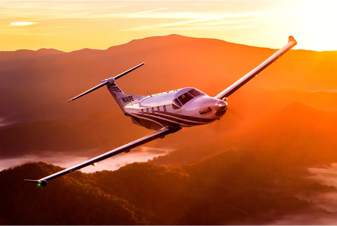 Pilatus PC-12 flying above mountain ridges at sunset